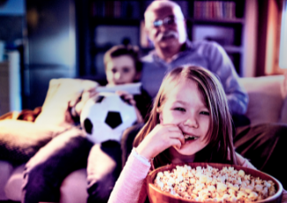 Young girl watches tv and eats popcorn